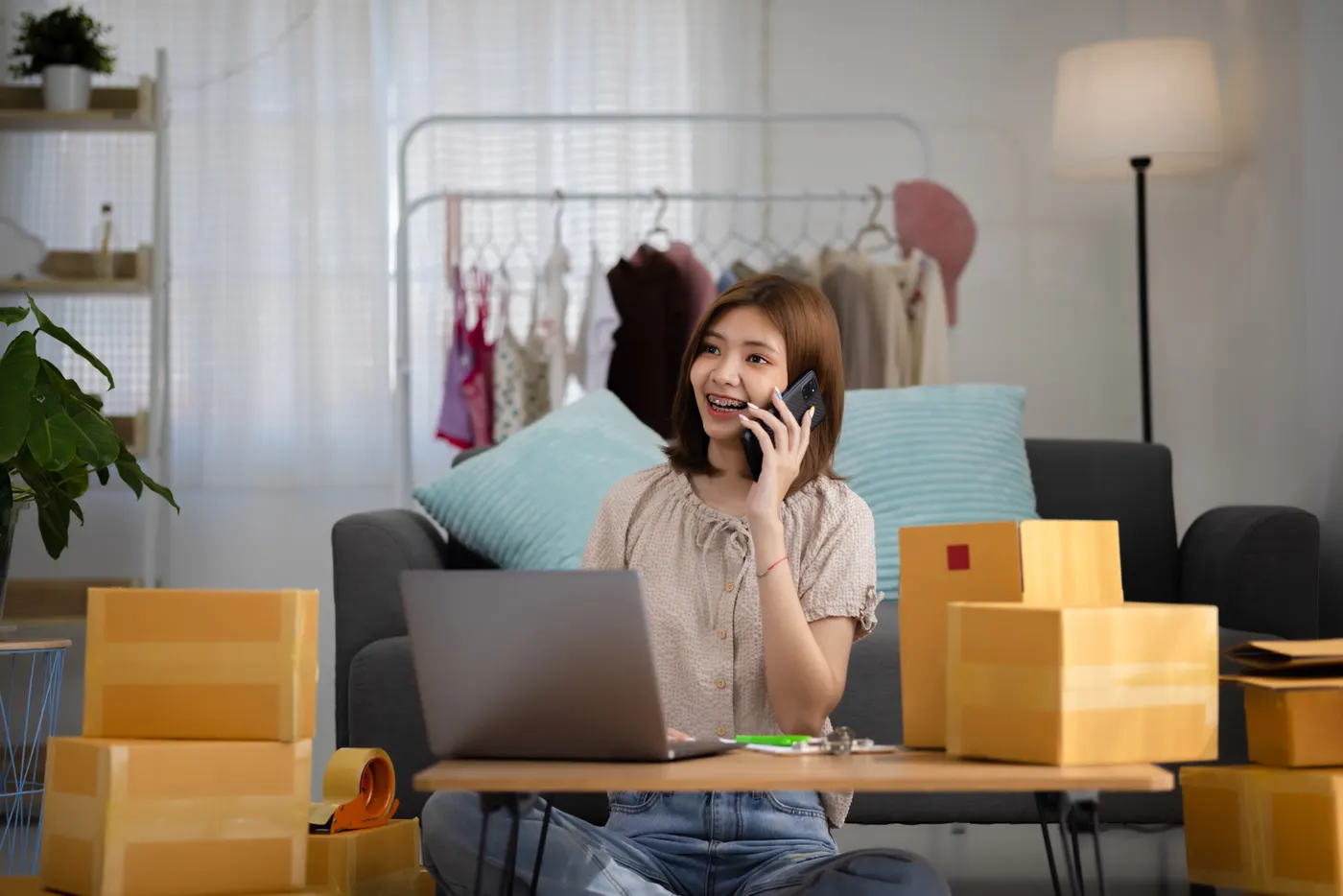 Woman taking an order call beside parcels and a laptop