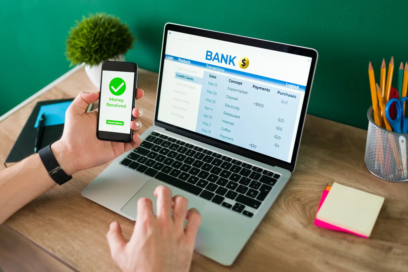 Person using a banking app on a phone and laptop