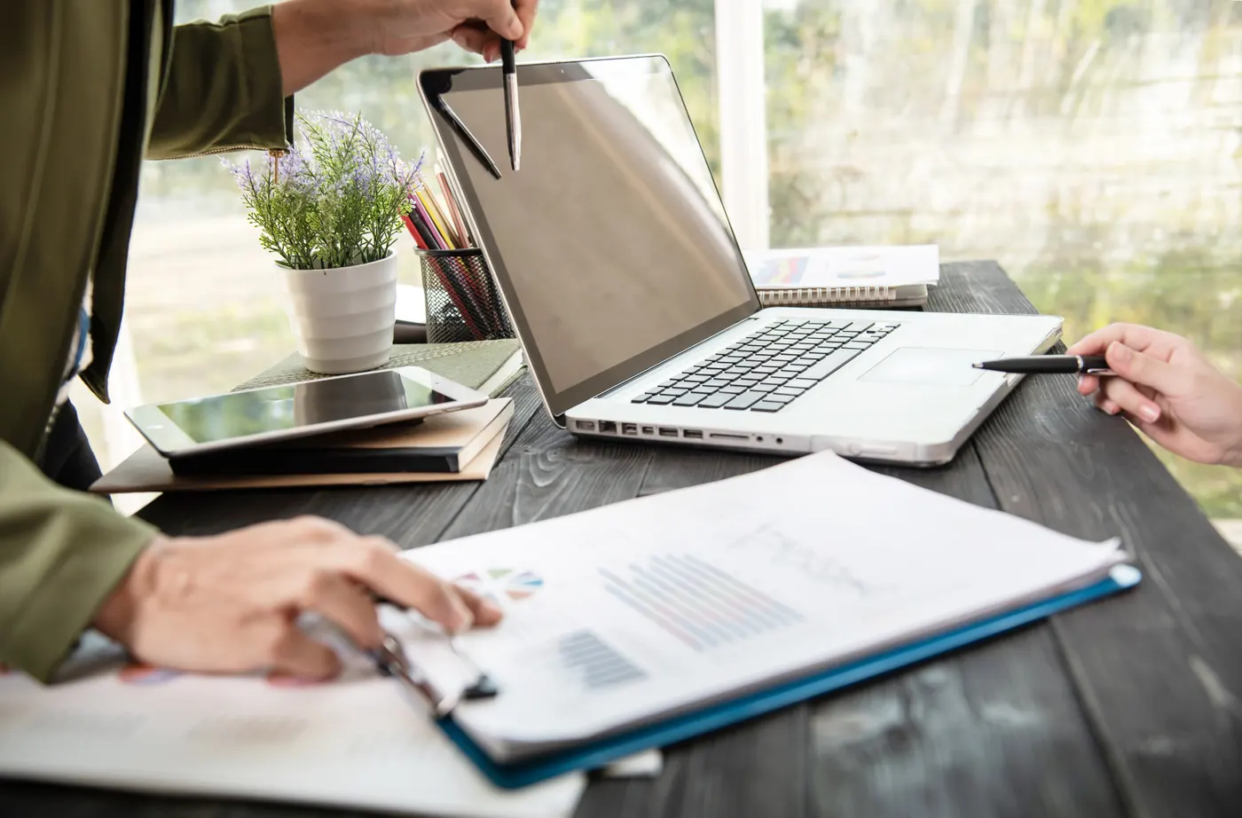 Hands on a laptop at a desk with papers
