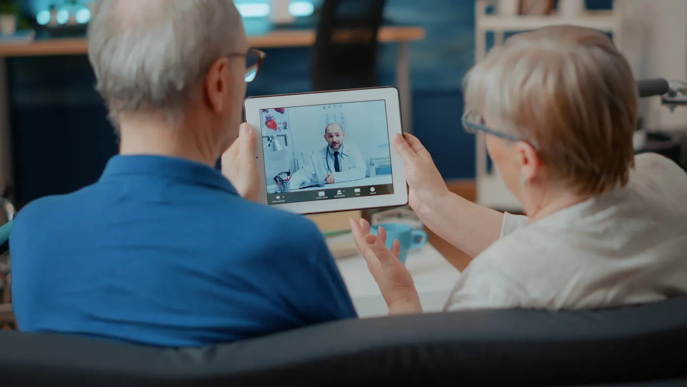 Senior couple on a tablet video call with a doctor at home
