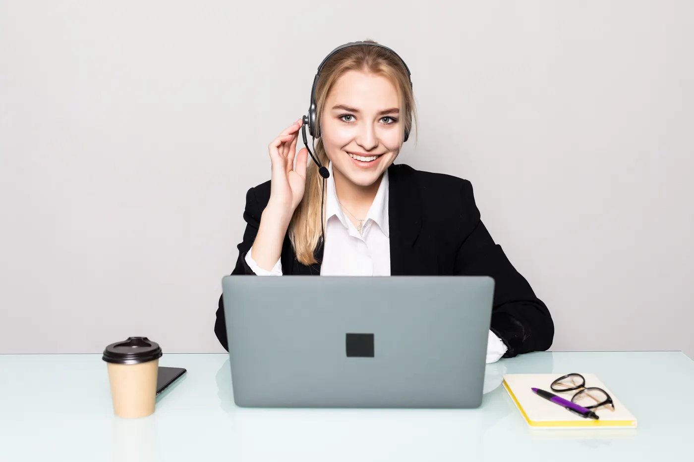 Smiling support agent wearing a headset at a laptop