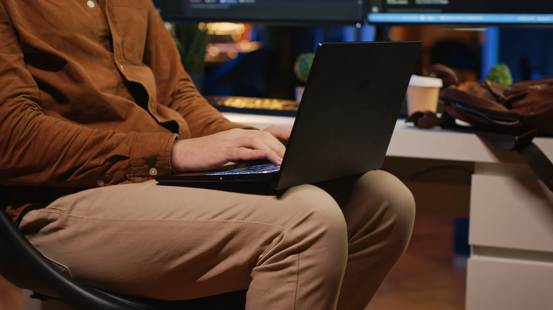 Hands typing on a laptop at a desk